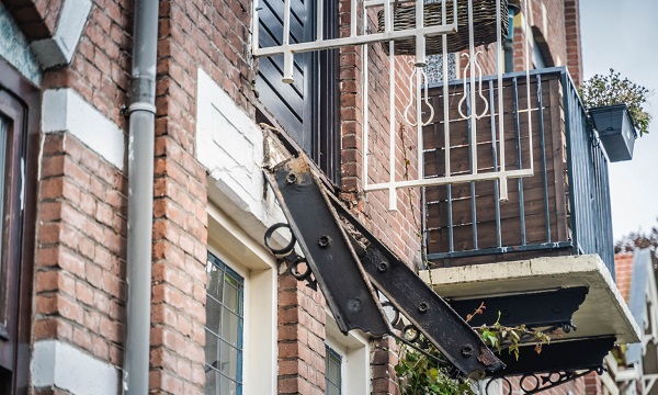Balkon met vader en zoon erop stort neer