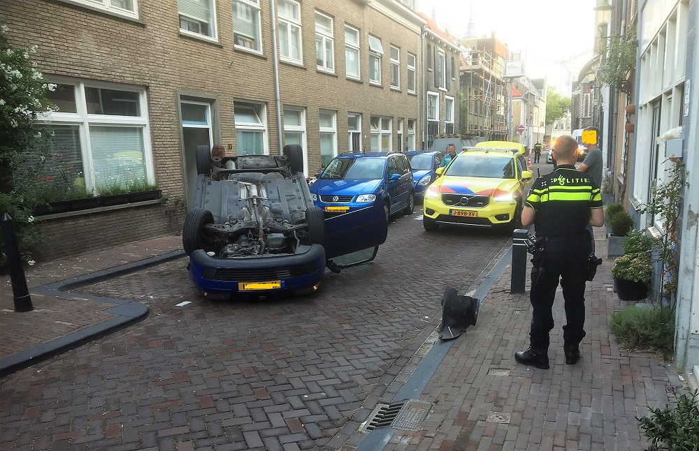 Vrouw kruipt zelf uit haar op de kop liggende auto