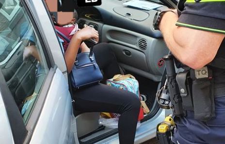 Vrouw als inzittende van auto met baby in draagzak op haar buik 