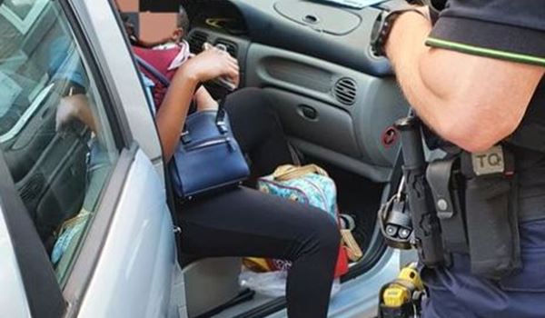 Vrouw als inzittende van auto met baby in draagzak op haar buik 